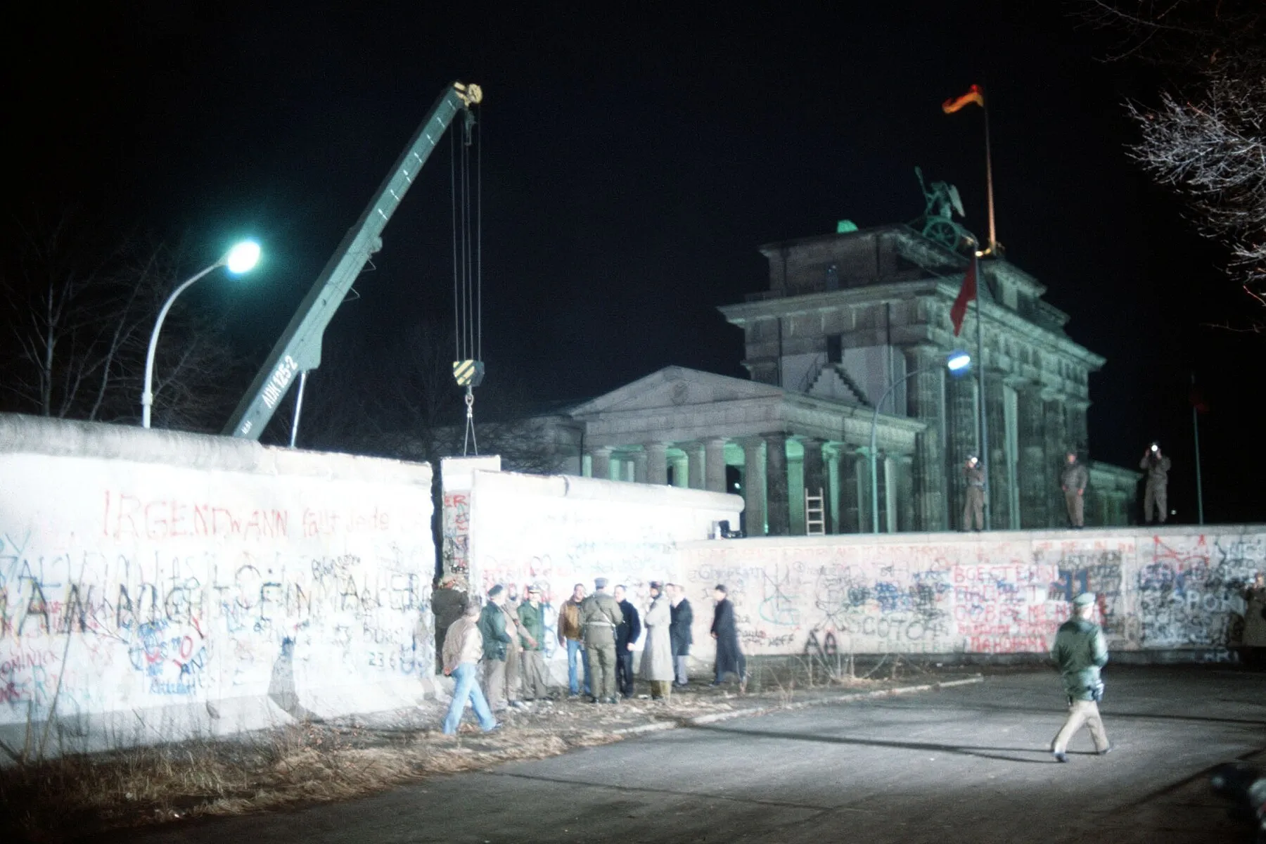 Berlin, December 1989: a crane removes a section of the Wall at the Brandenburg Gate — the list of walls turns into the blueprint of a door (U.S. Air Force photo, SSgt F. Lee Corkran).